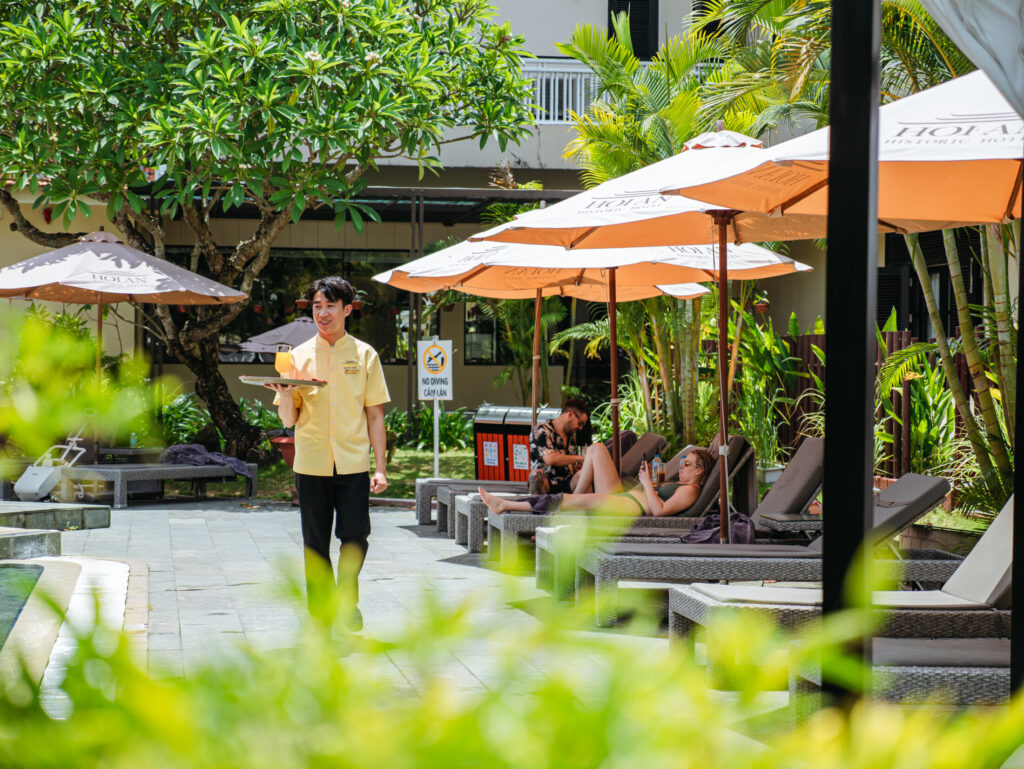 Guest enjoying the tropical swimming pool and lush gardens at Hoi An Historic Hotel in Hoi An